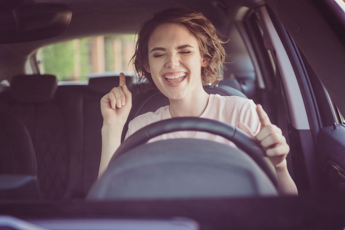 Donna in automobile canta e sorride