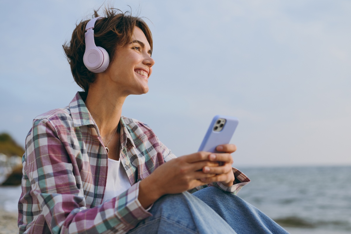 Ragazza con cuffie e telefono ascolta musica al mare