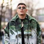 Nerissima Serpe indossa sneakers bianche, occhiali da sole neri, pantaloni neri, una t-shirt nera, una collana dorata e un bomber verde stampato con camicia coordinata, all’esterno della sfilata di MSGM durante la Milano Fashion Week dedicata alla moda donna.