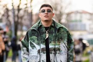 Nerissima Serpe indossa sneakers bianche, occhiali da sole neri, pantaloni neri, una t-shirt nera, una collana dorata e un bomber verde stampato con camicia coordinata, all’esterno della sfilata di MSGM durante la Milano Fashion Week dedicata alla moda donna.