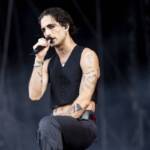 Damiano David in canotta e jeans neri, con il microfono in mano