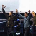 Liam Gallagher e Noel Gallagher sul palco che salutano a mani alzate i fan