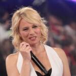 Maria De Filippi in gilet bianco con il microfono in mano