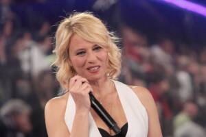 Maria De Filippi in gilet bianco con il microfono in mano