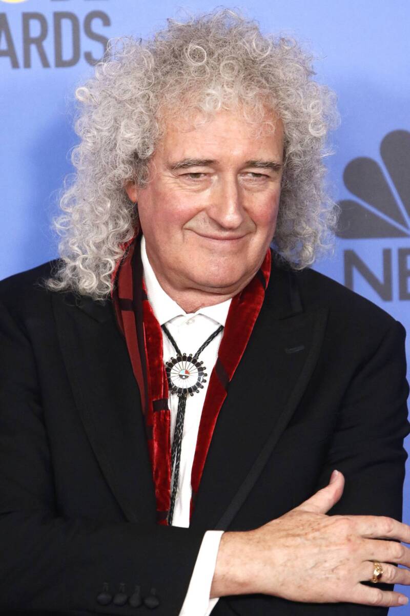 Brian May in abito nero con le braccia incrociate