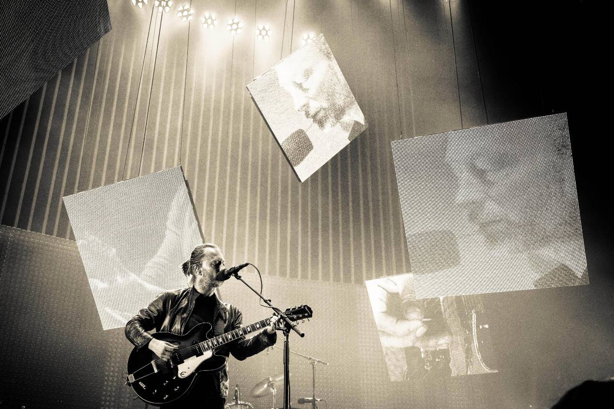 Tom Yorke che suona la chitarra e canta in un immagine in bianco e nero