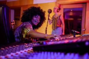 Produttrice musicale in studio di registrazione durante una sessione con una cantante.